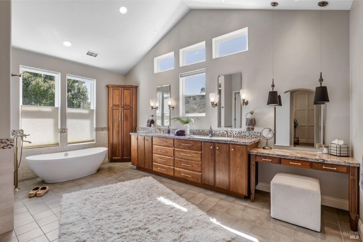 The bathroom features a double vanity, a soaking tub, and a vanity with a mirror and stool.