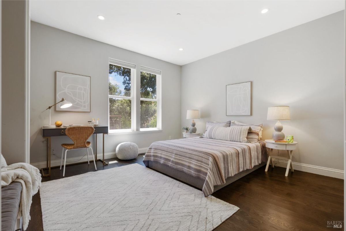 Minimalist bedroom featuring a striped bedspread, soft lighting, and a writing desk.