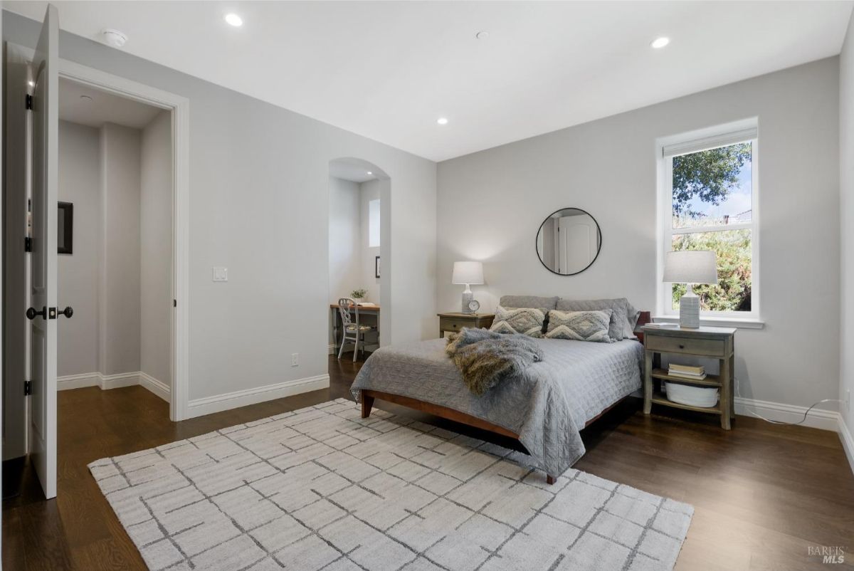 Elegant bedroom with a plush bed, neutral tones, and a small reading nook.