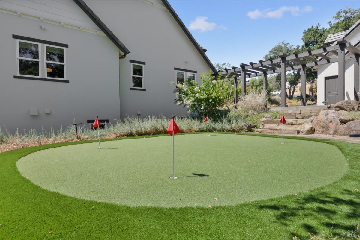 The backyard features a putting green with red flags.