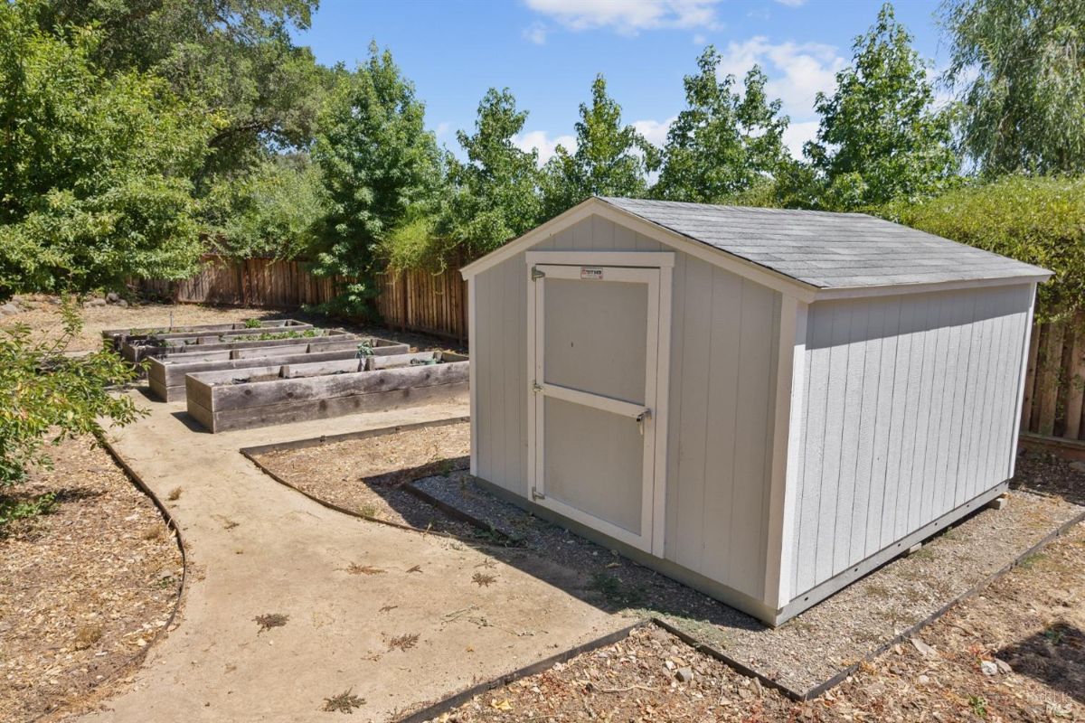 The backyard features raised garden beds and a small shed.