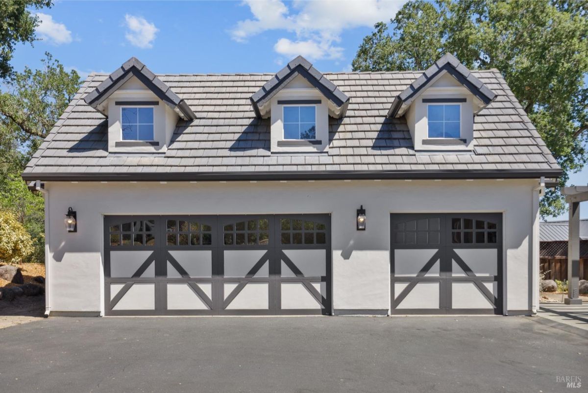 The detached garage has three doors and dormer windows.