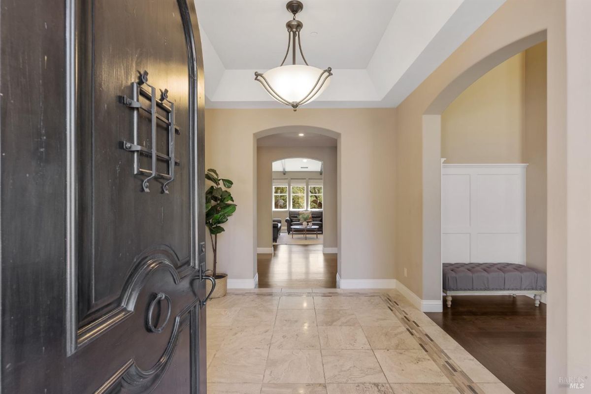 Entryway featuring a decorative black door and a view into a bright hallway with arches.