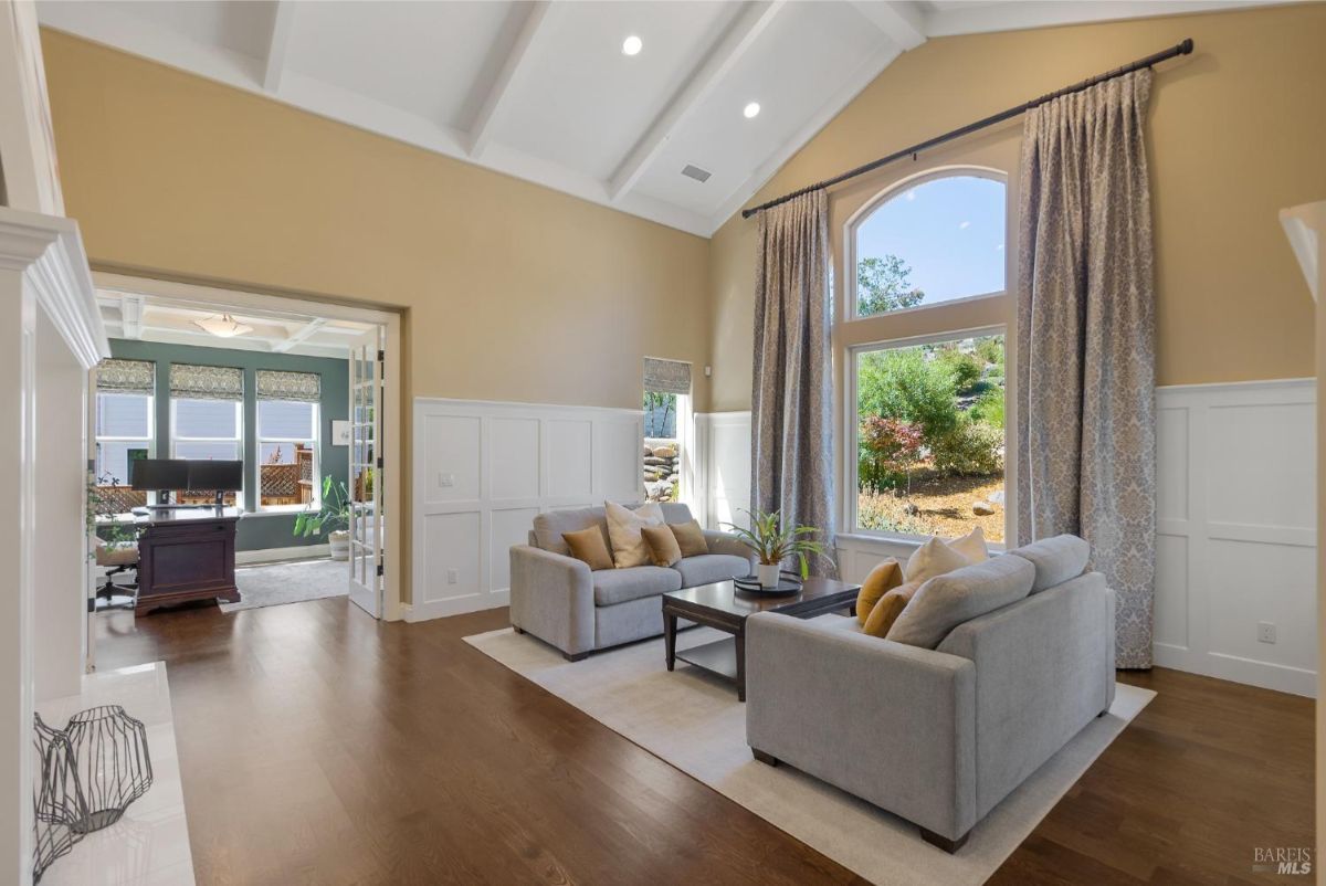 Spacious living room with high ceilings and large windows overlooking a landscaped garden.