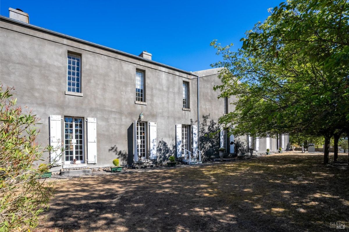 Two-story building with large windows and white shutters against a gray stucco exterior.