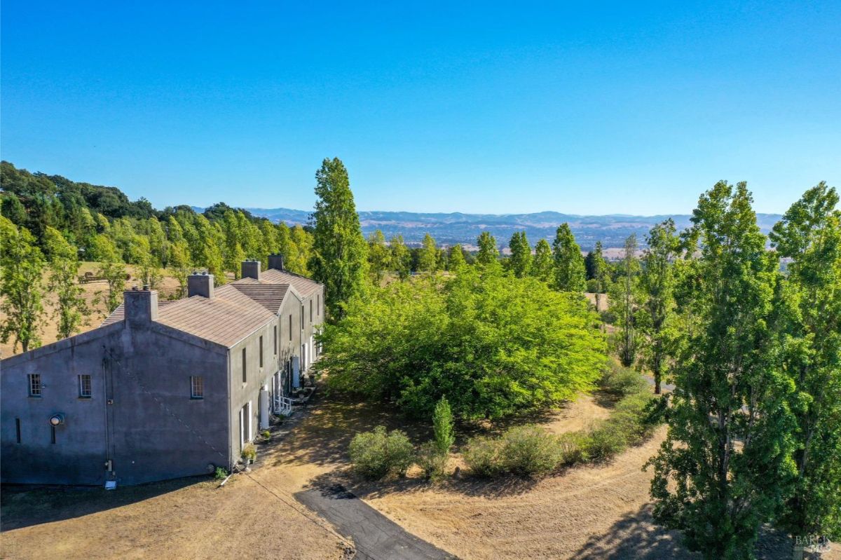 Aerial view of a large property with a rectangular building, circular garden, and surrounding trees.