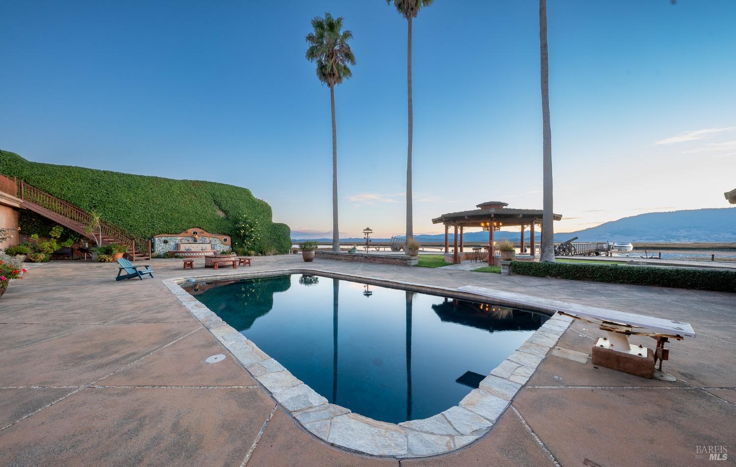 This inviting pool area offers a serene escape with its crystal-clear water reflecting the beautiful surroundings. The palm trees, gazebo, and lush greenery create a tranquil atmosphere for relaxation and outdoor enjoyment.