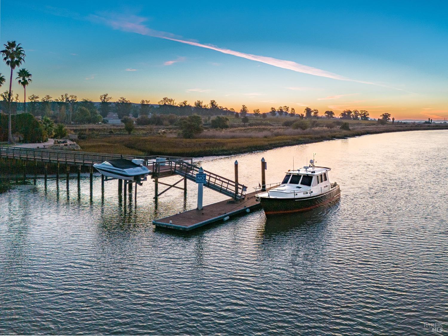 A charming private dock extends into the calm waters, offering a picturesque spot to moor a boat and soak in the tranquil beauty of the surrounding landscape. As the sun dips below the horizon, casting a warm glow on the scene, it creates a perfect setting for peaceful reflection and enjoying the serenity of nature.