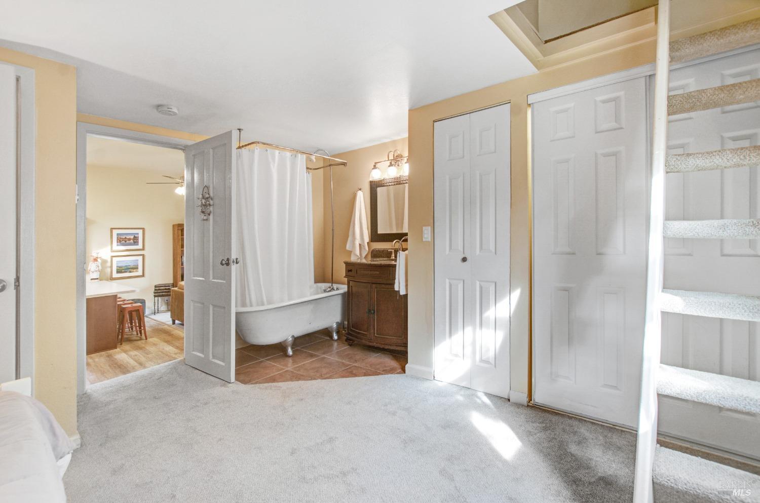 A clawfoot tub anchors this cozy bathroom, adding a touch of vintage charm. The space also features a small vanity and a unique door that opens directly into the bedroom.