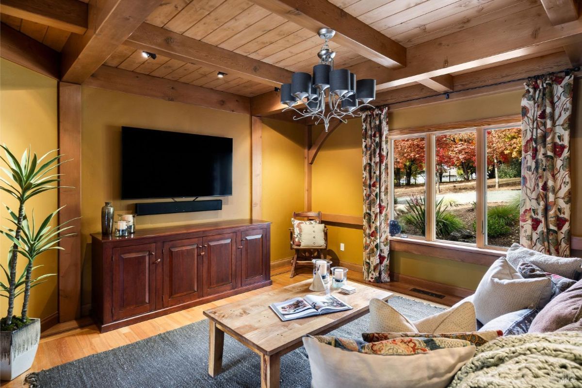 Living room with exposed wooden beams, large windows, and comfortable furniture.