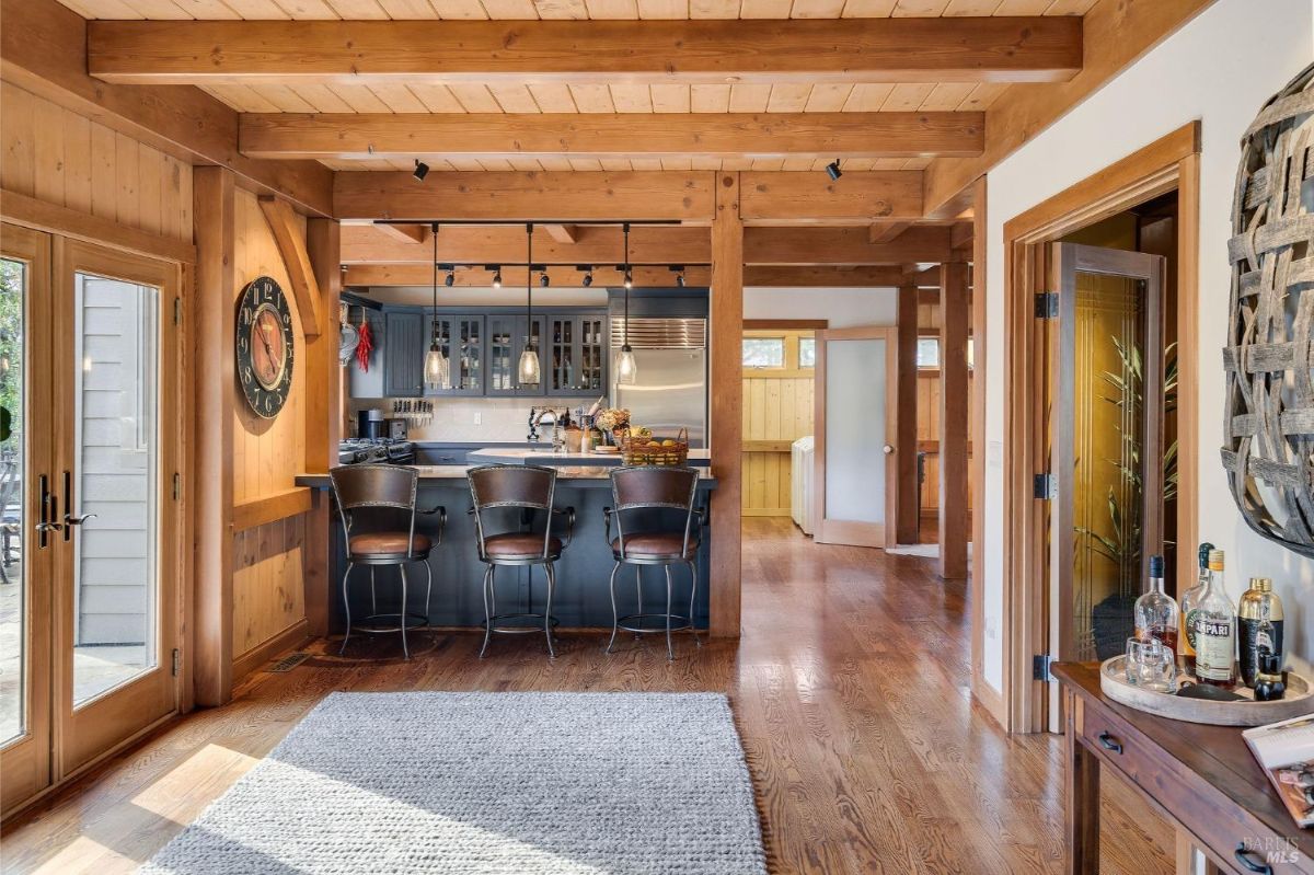 Kitchen with dark cabinetry, a pot rack above the sink, and expansive windows framing the outdoor scenery.