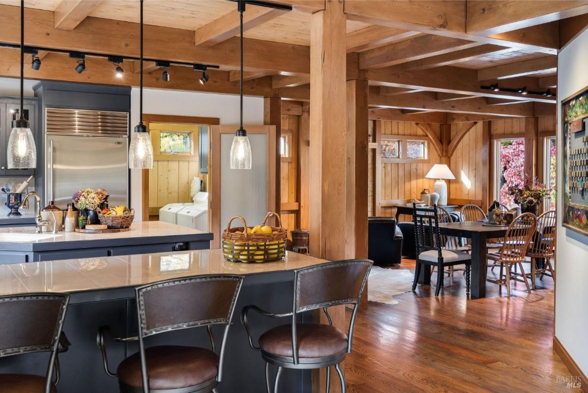 Kitchen island with pendant lights overlooks a bar area and dining space, showcasing an open and functional layout.