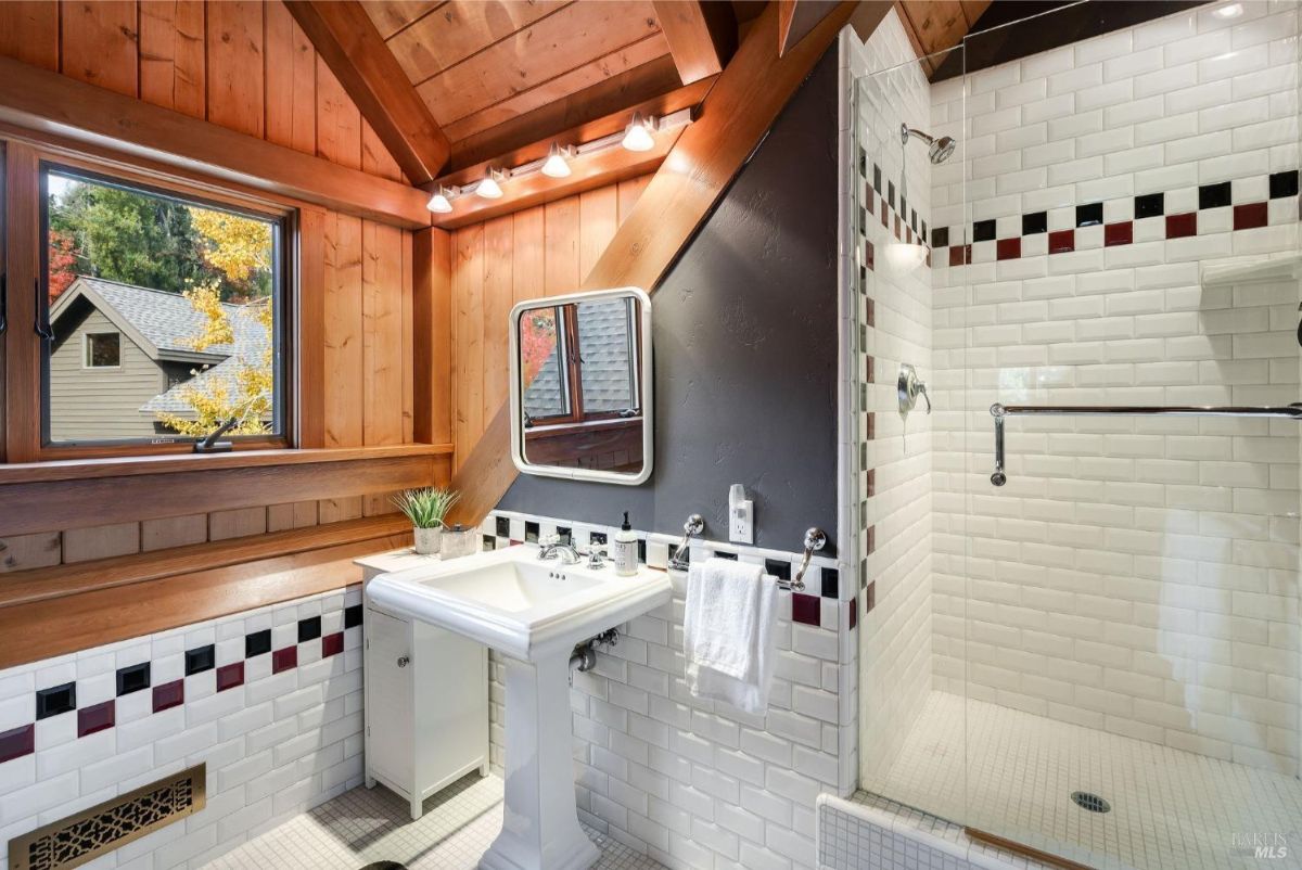 Bathroom with white subway tiles, wood ceiling beams, and a glass-enclosed shower.