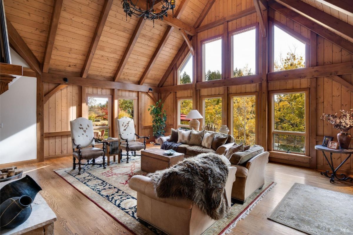 Living room with high vaulted wooden ceilings and large windows overlooking a landscaped yard.