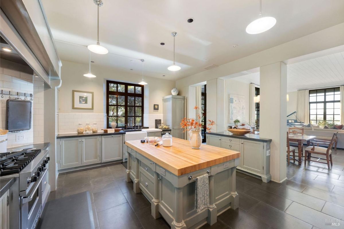 Overview of the kitchen highlighting the island with stools and stainless steel range with a hood