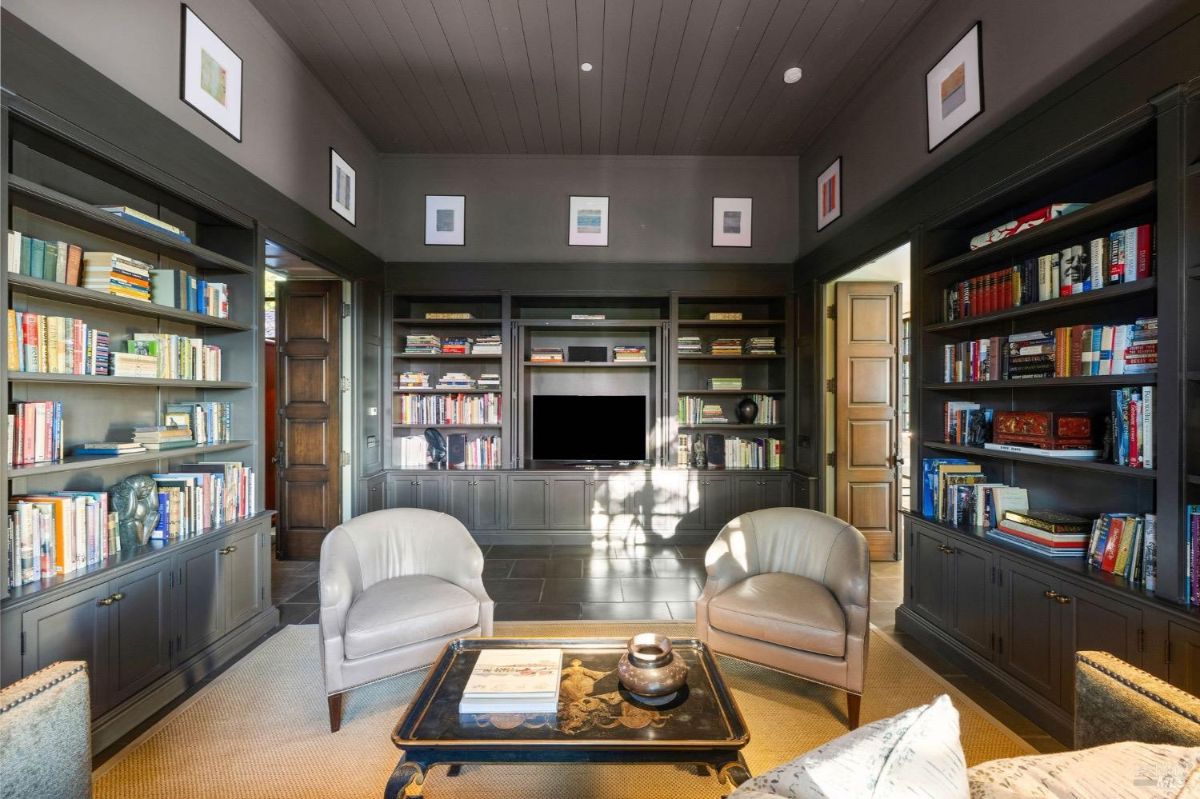 Library with built-in bookshelves, a TV, and two upholstered chairs.