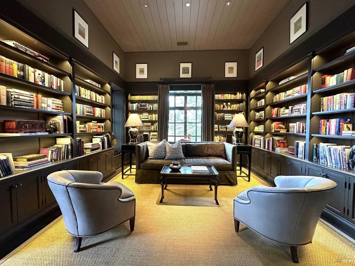 Large library with floor-to-ceiling bookshelves, a central seating area, and soft lighting.