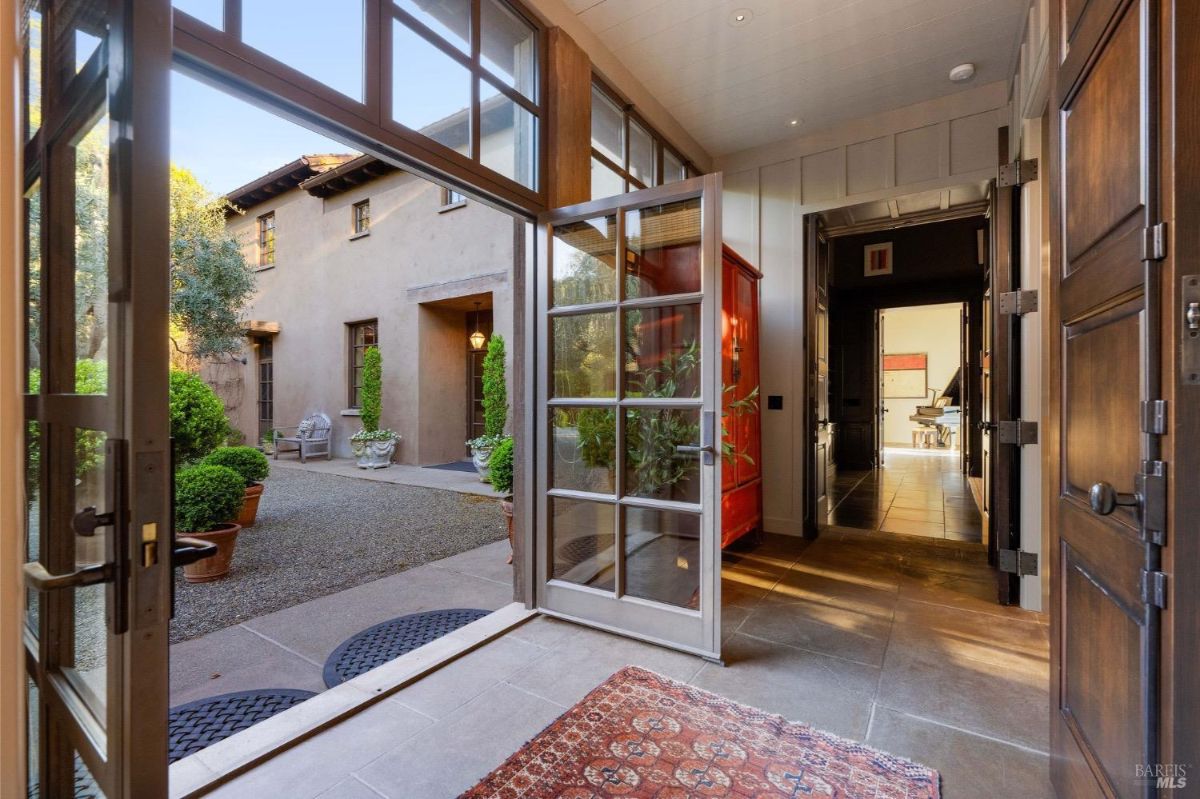 Entrance features an open door leading to a courtyard with potted plants and seating.