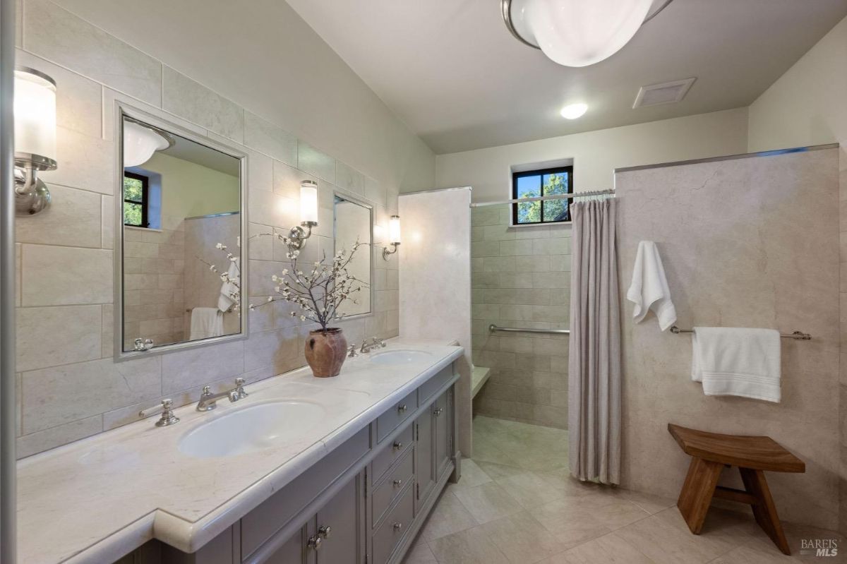 Double vanity bathroom with marble countertops and a walk-in shower.