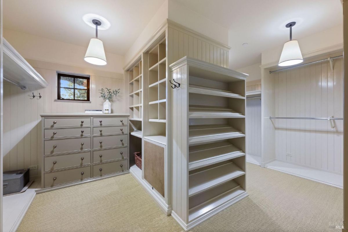 Walk-in closet with built-in drawers, shelves, and hanging space under soft ceiling lights.