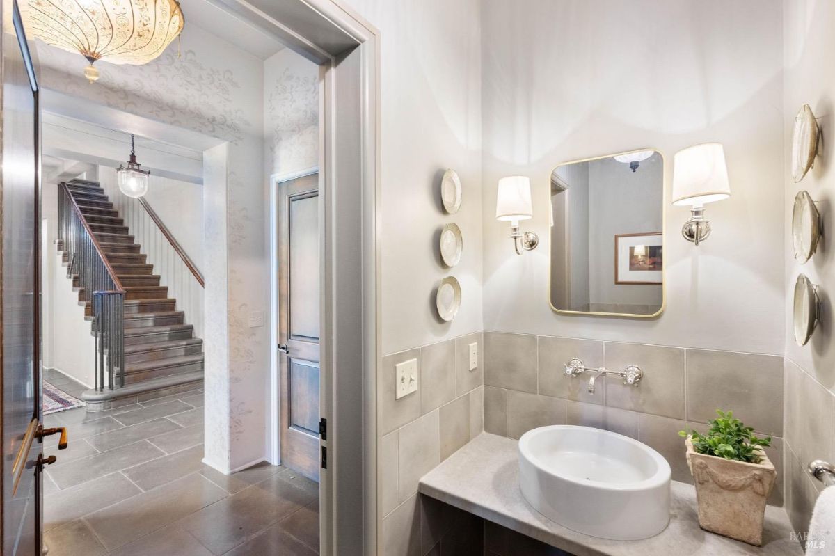 Small powder room with a single basin sink and decorative plates on the wall.