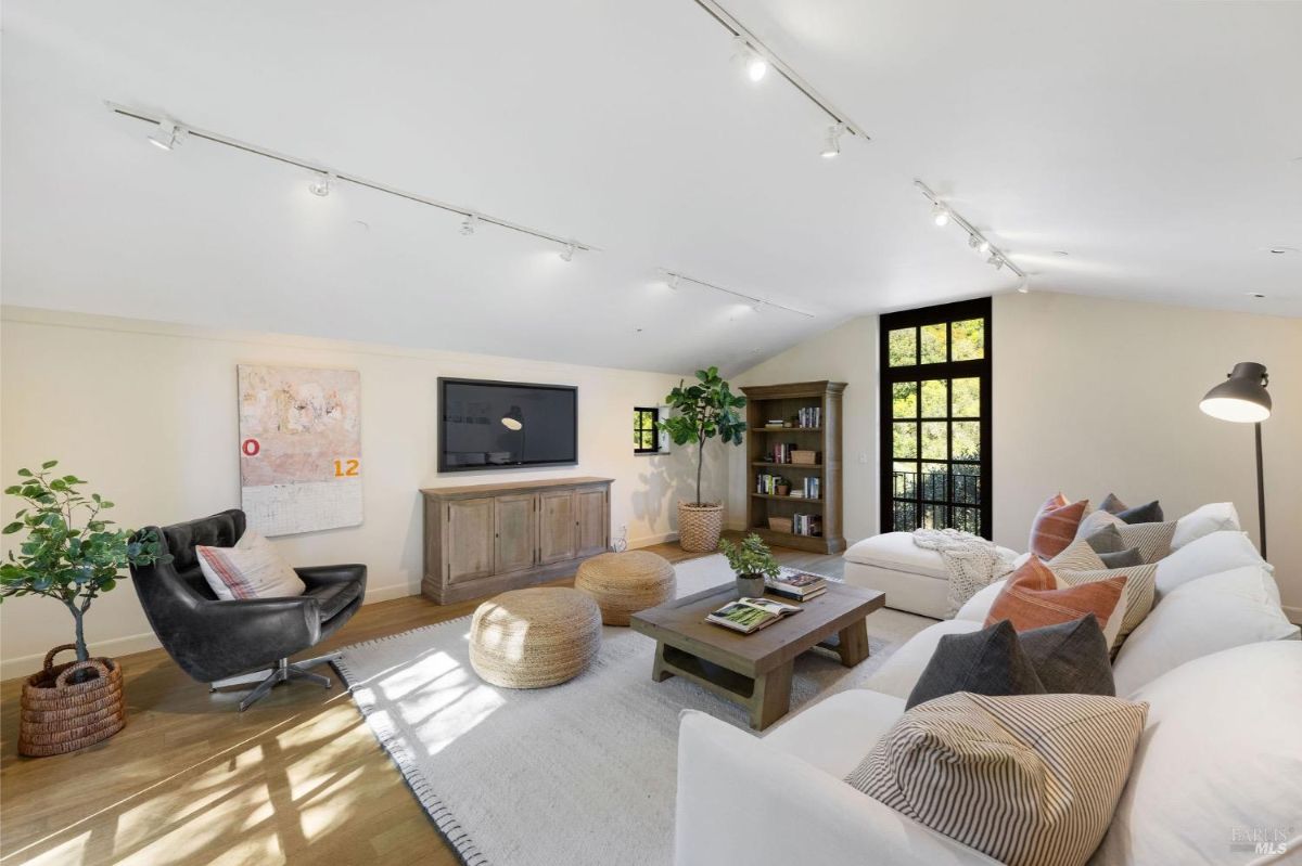 Family room with a large TV, bookshelves, and modern furniture.