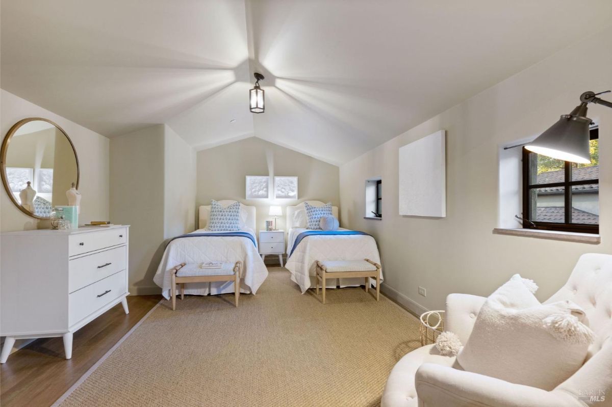 Twin bed setup in a compact bedroom with slanted ceiling and simple decor.