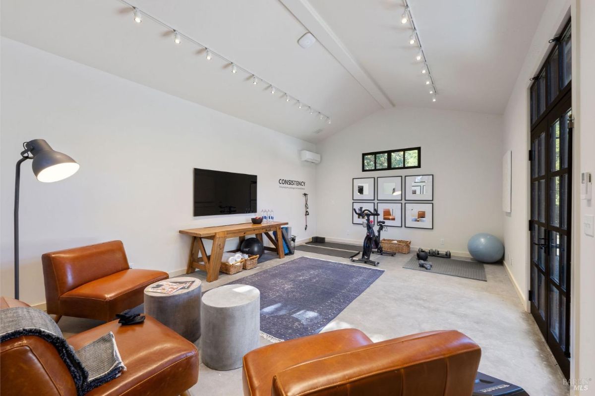 Gym area featuring leather chairs, workout equipment, and a large TV.