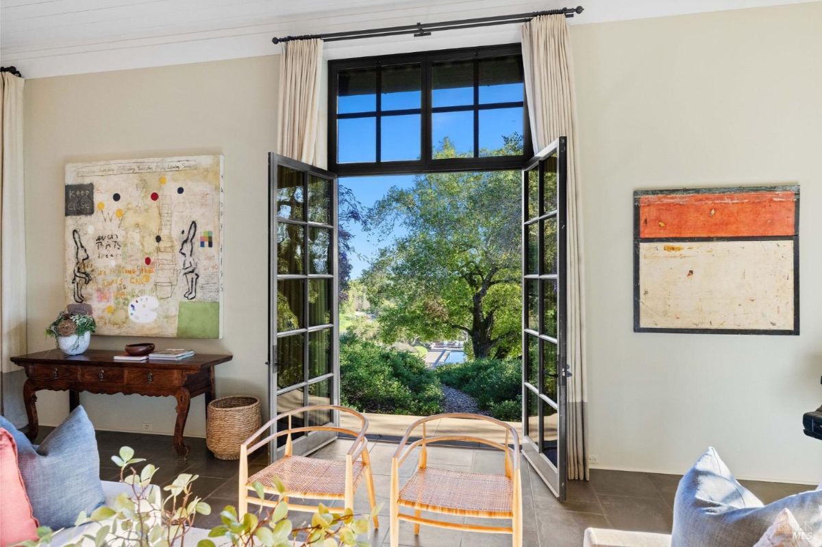 Living room with open French doors leading to an outdoor view of trees and landscaping.