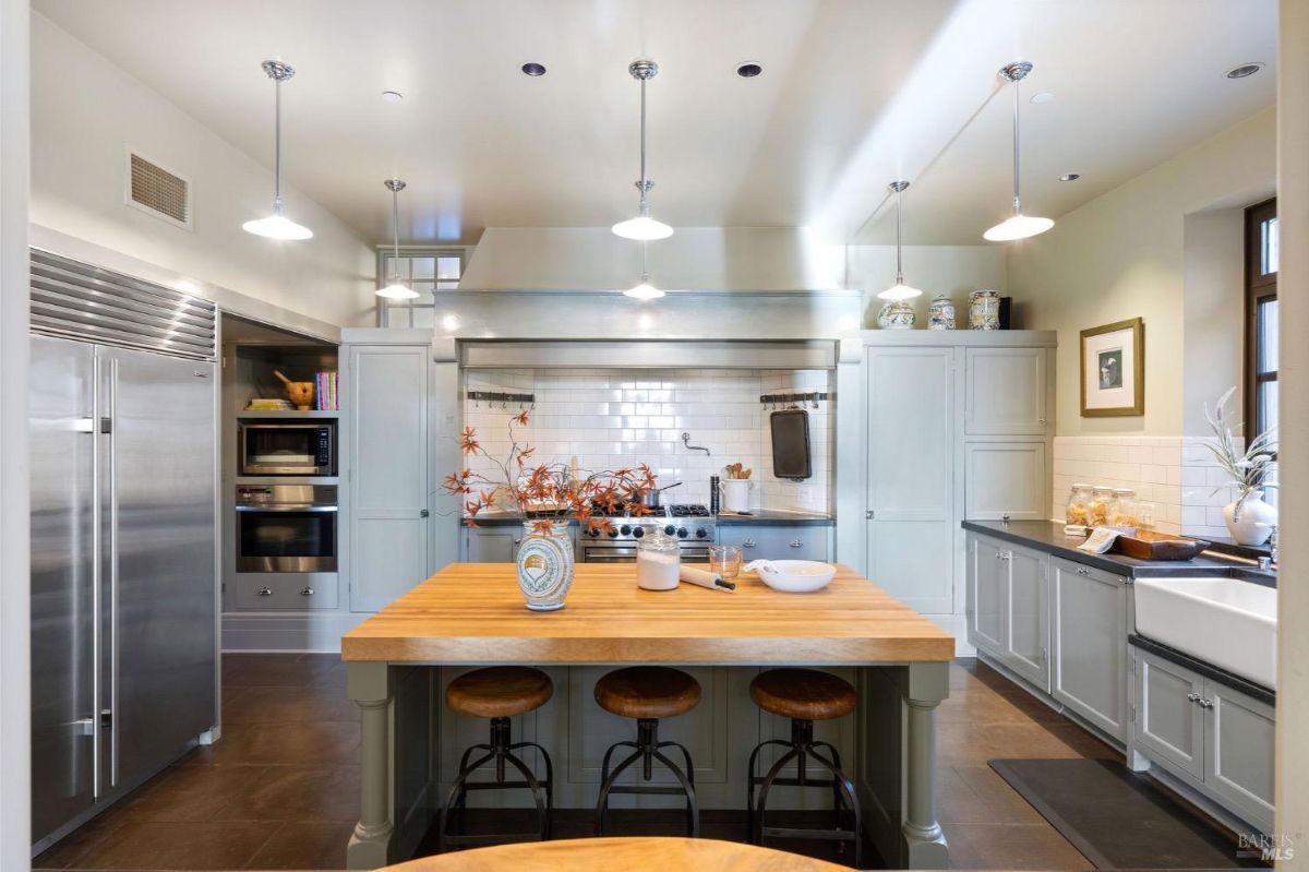 Kitchen with a central wooden island, gray cabinetry, and stainless steel appliances.