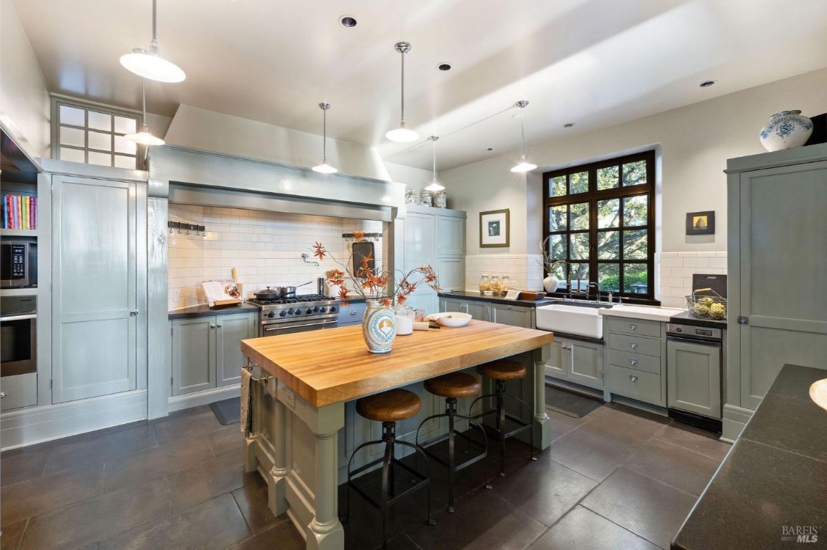 Kitchen features a farmhouse sink, white subway tiles, and a view of the outdoors through black-framed windows.