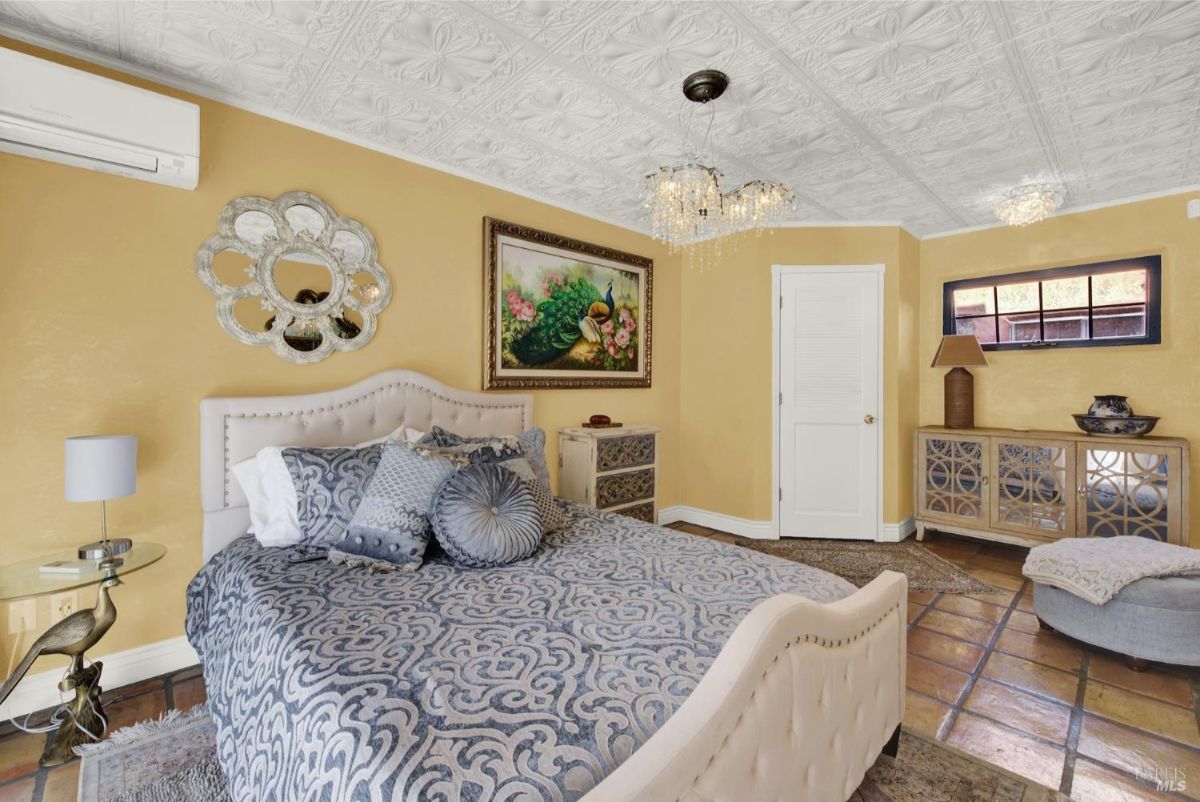 Bedroom features a luxurious bed with intricate patterns, a chandelier, and elegant decor.