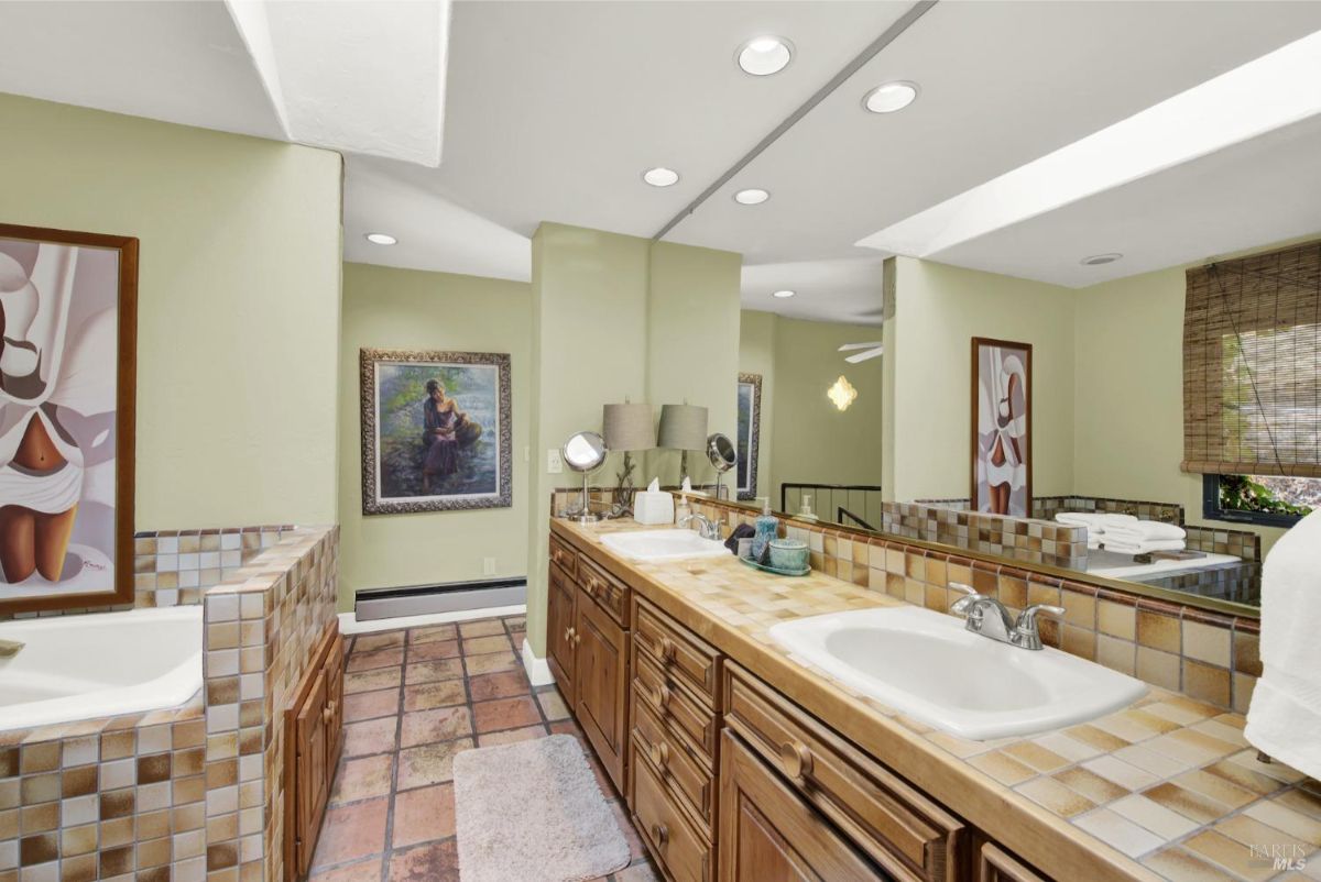 The bathroom has two sinks, a large mirror and tiled floors.