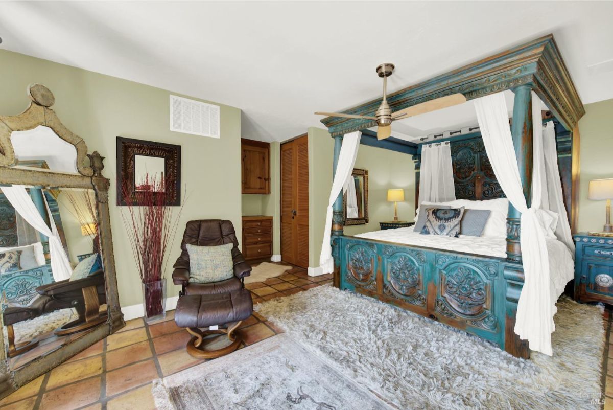 Bedroom with a large, intricately carved four-poster bed covered with a white canopy and colorful bedding