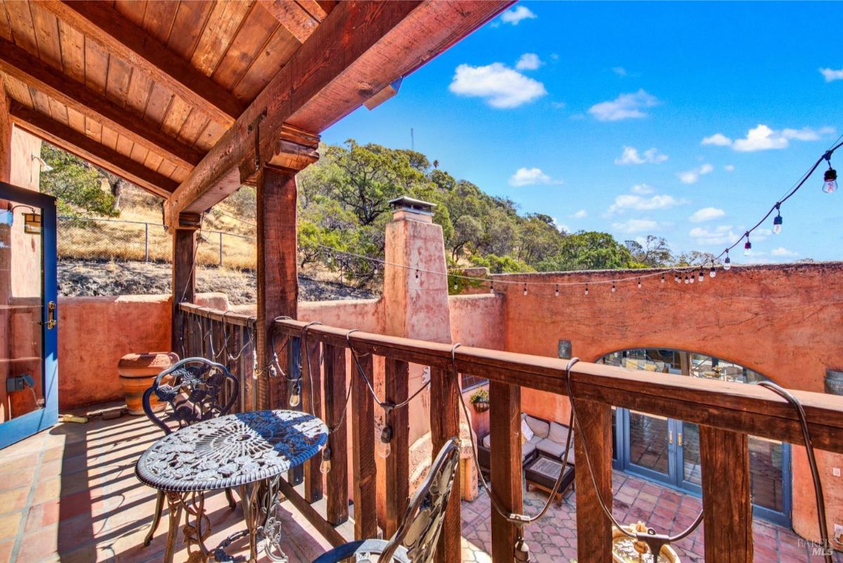 The balcony overlooks the courtyard and has a table and chairs.