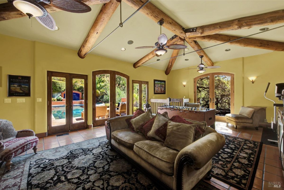 Recreational space featuring exposed wooden beams, large windows, and a foosball table.