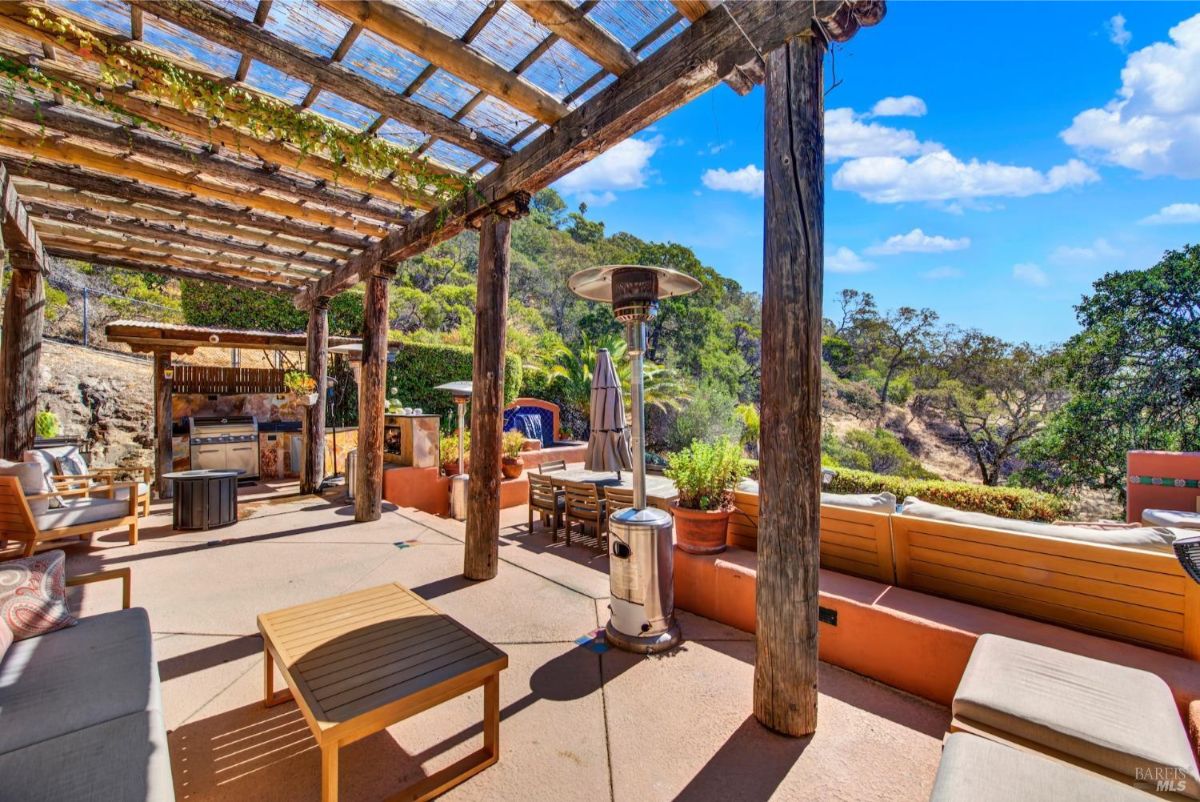 The patio has a pergola, an outdoor kitchen, seating areas, and a heater.