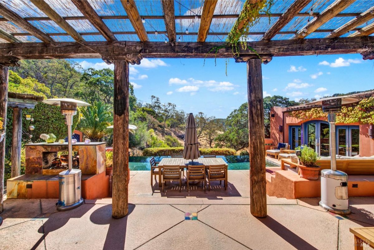 The patio has a pergola, a swimming pool, a dining table, and heaters.