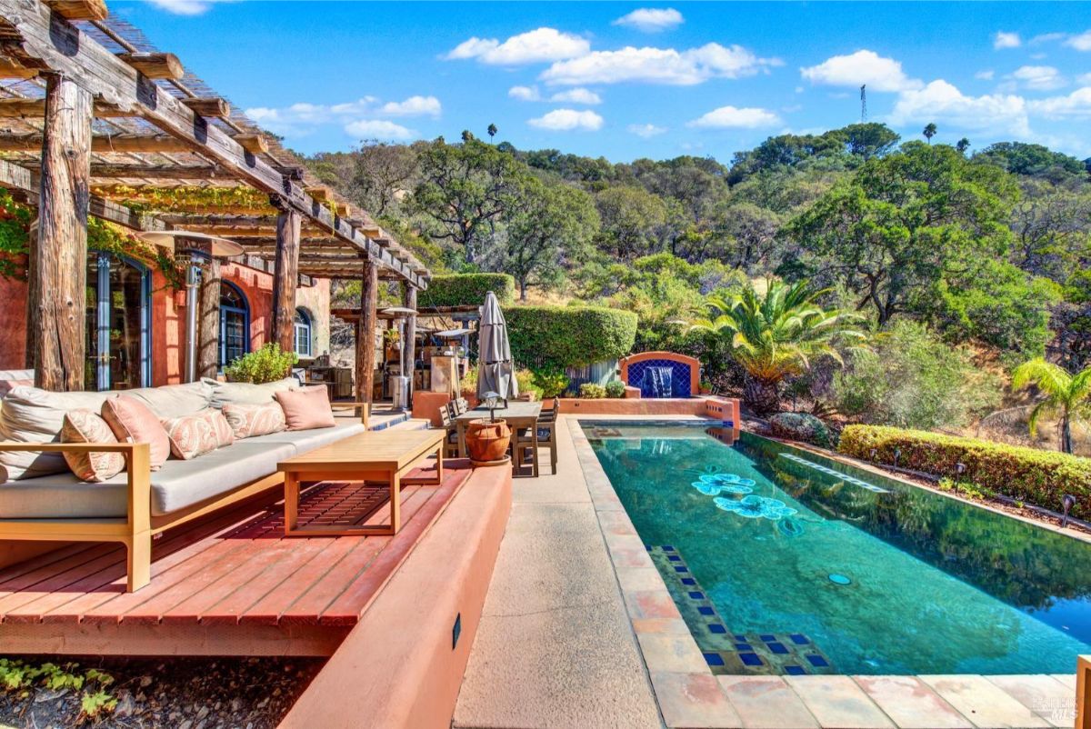 The pool area has a deck, a pergola, and a view of the hills.