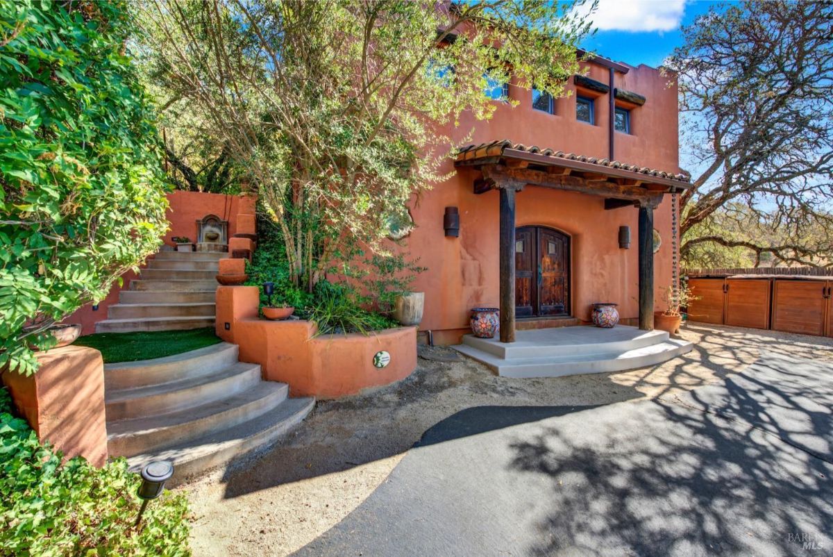 Entryway with a rustic terracotta façade surrounded by greenery and decorative stairs.