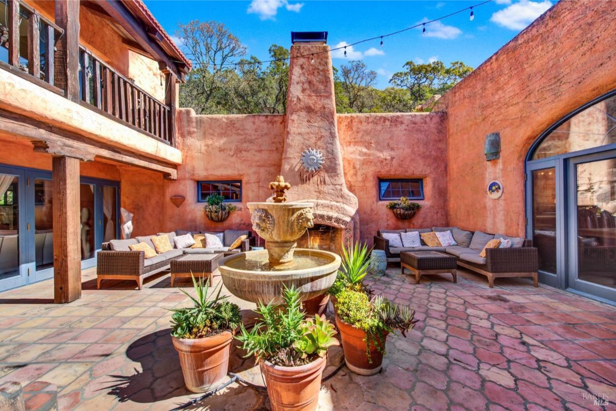 The courtyard has a fountain, a fireplace, seating areas, and a brick-paved floor.