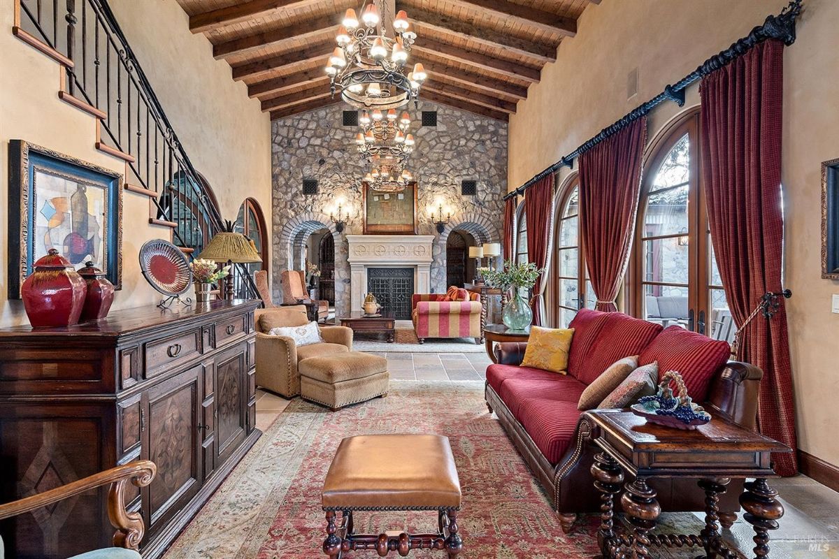 An angled view of the room displaying the fireplace, seating arrangements, and one of the arched entryways leading to another section of the property.