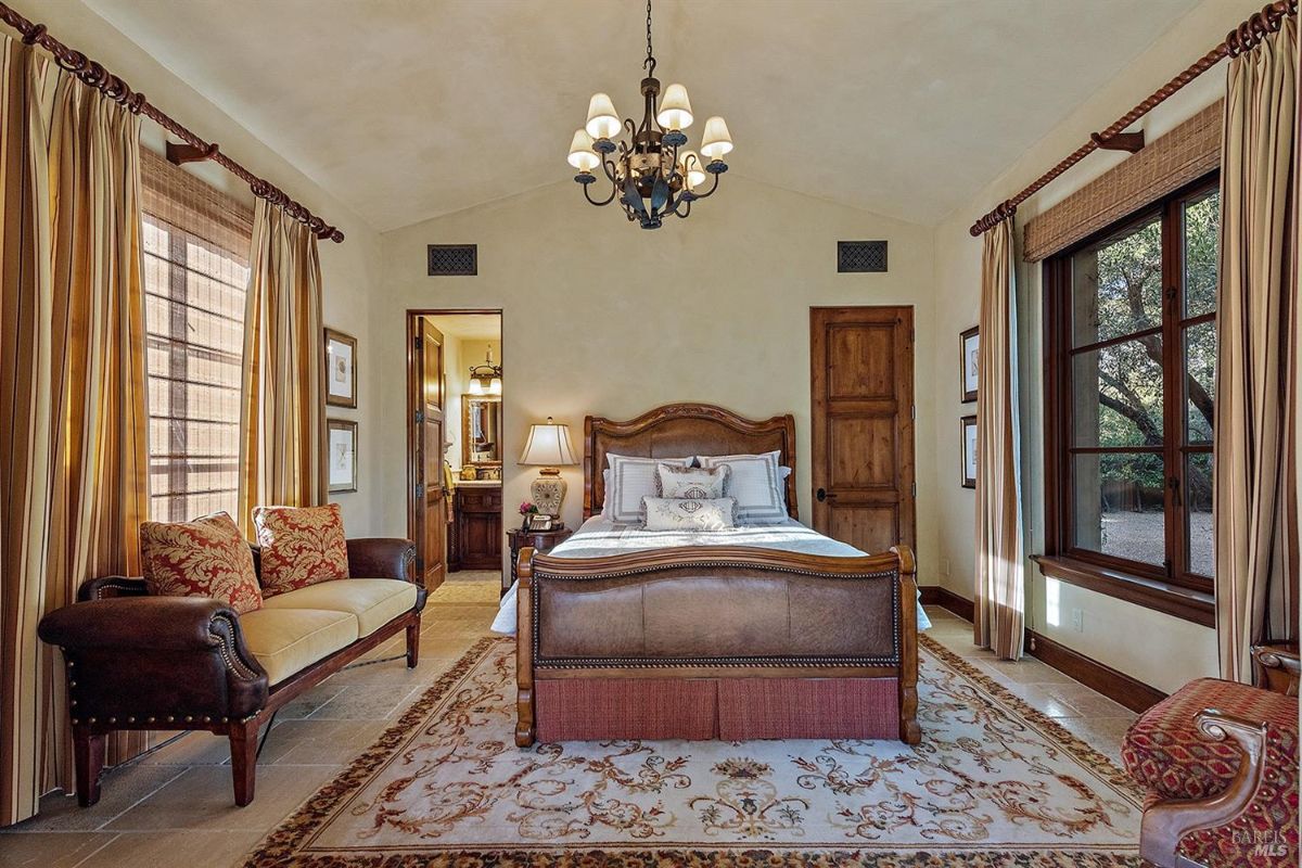 Another bedroom with a similar setup, showing a bed, a bench at the foot, and windows with curtains.