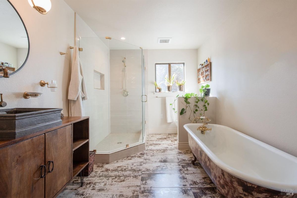 Bathroom with a freestanding bathtub, glass shower enclosure, and rustic wooden vanity.