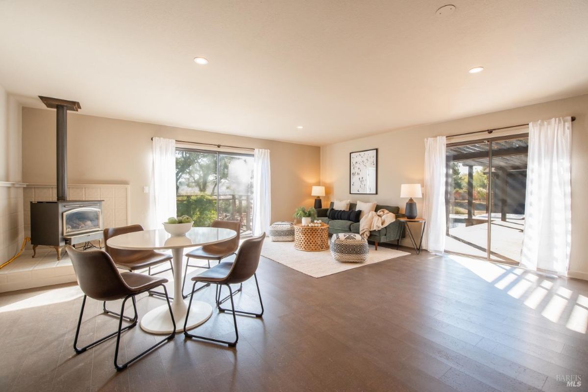 Bright living and dining space with a wood-burning stove, round dining table, and sliding doors to an outdoor area.