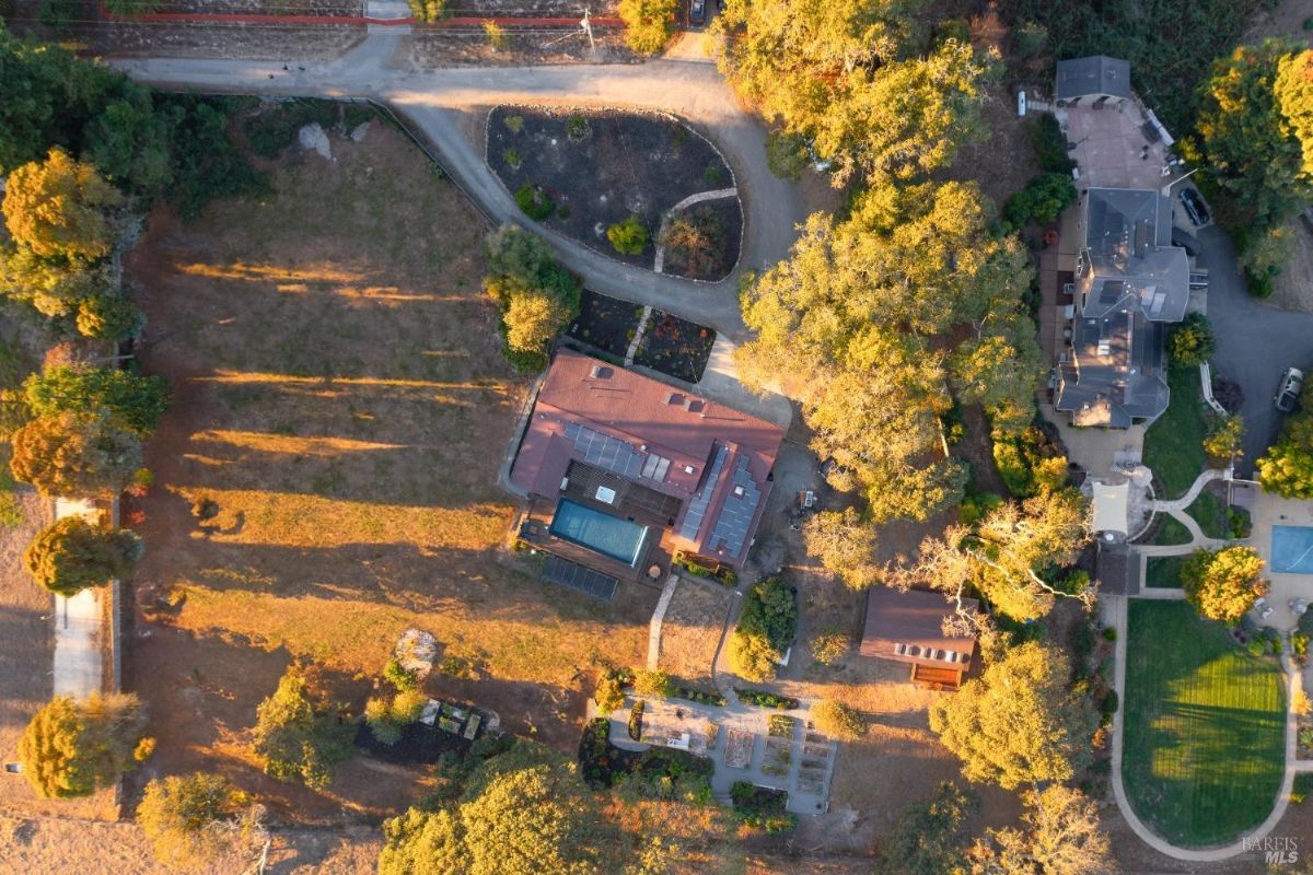 Aerial view of a property showing the house, pool, and surrounding gardens.