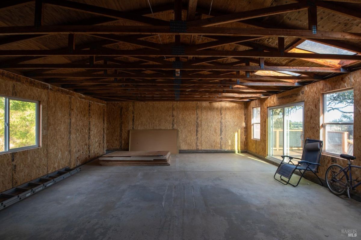 Large shed or garage interior with exposed beams and concrete flooring.