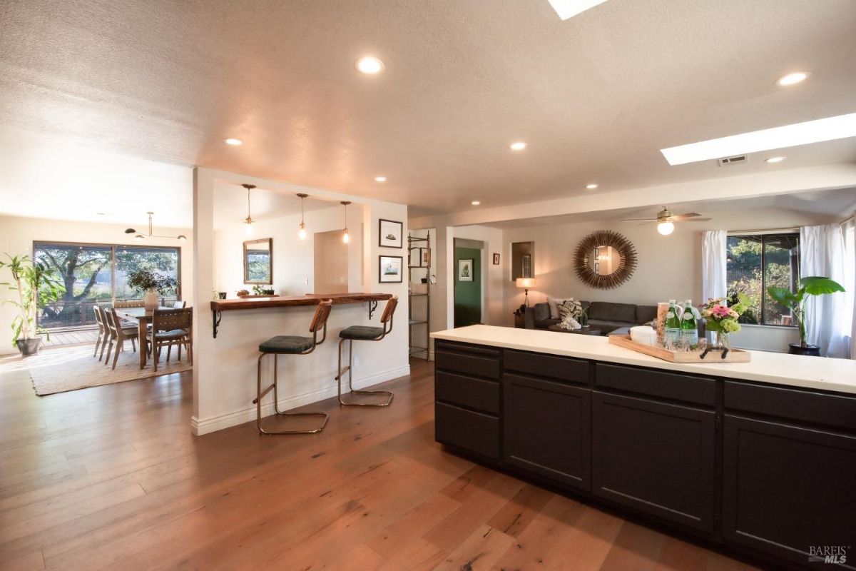 Open layout combining a kitchen bar with seating, dining area, and living space in a modern design.