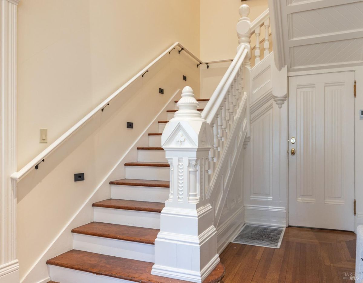 A beautifully crafted staircase with white wooden banisters and rich hardwood steps. The staircase design highlights the home's traditional architecture with intricate details.