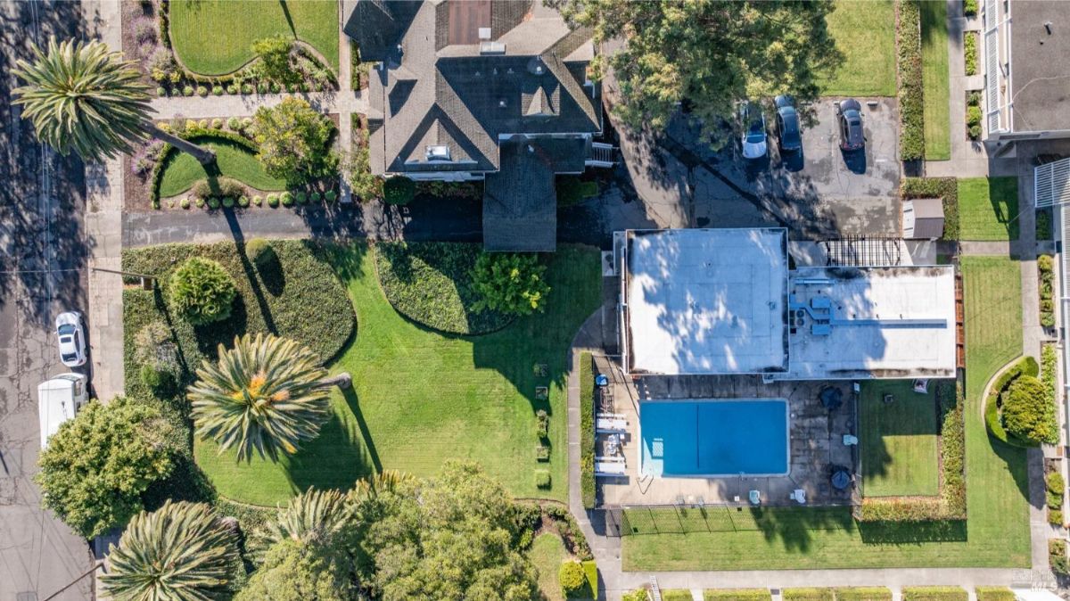  A bird's-eye view of the property reveals well-manicured landscaping, a central building surrounded by lush greenery, and a swimming pool with adjacent seating areas. The layout offers a mix of elegance and functionality in an expansive outdoor space.